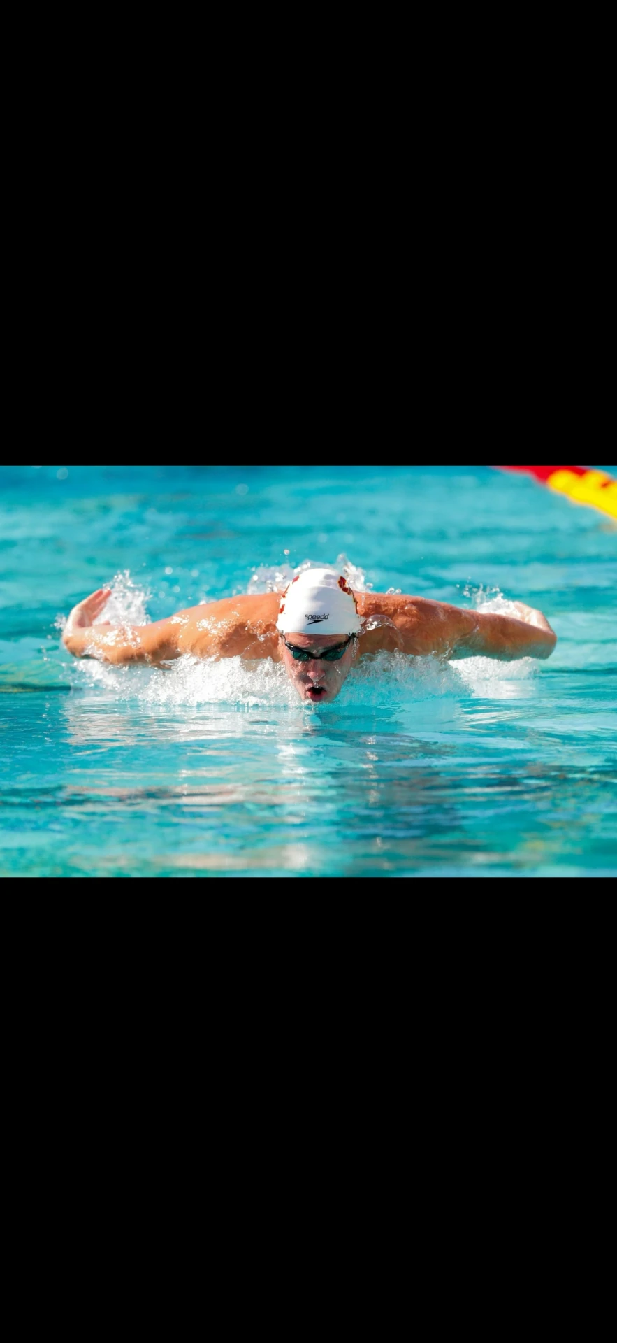 Swimmer powering through a butterfly race in an outdoor pool