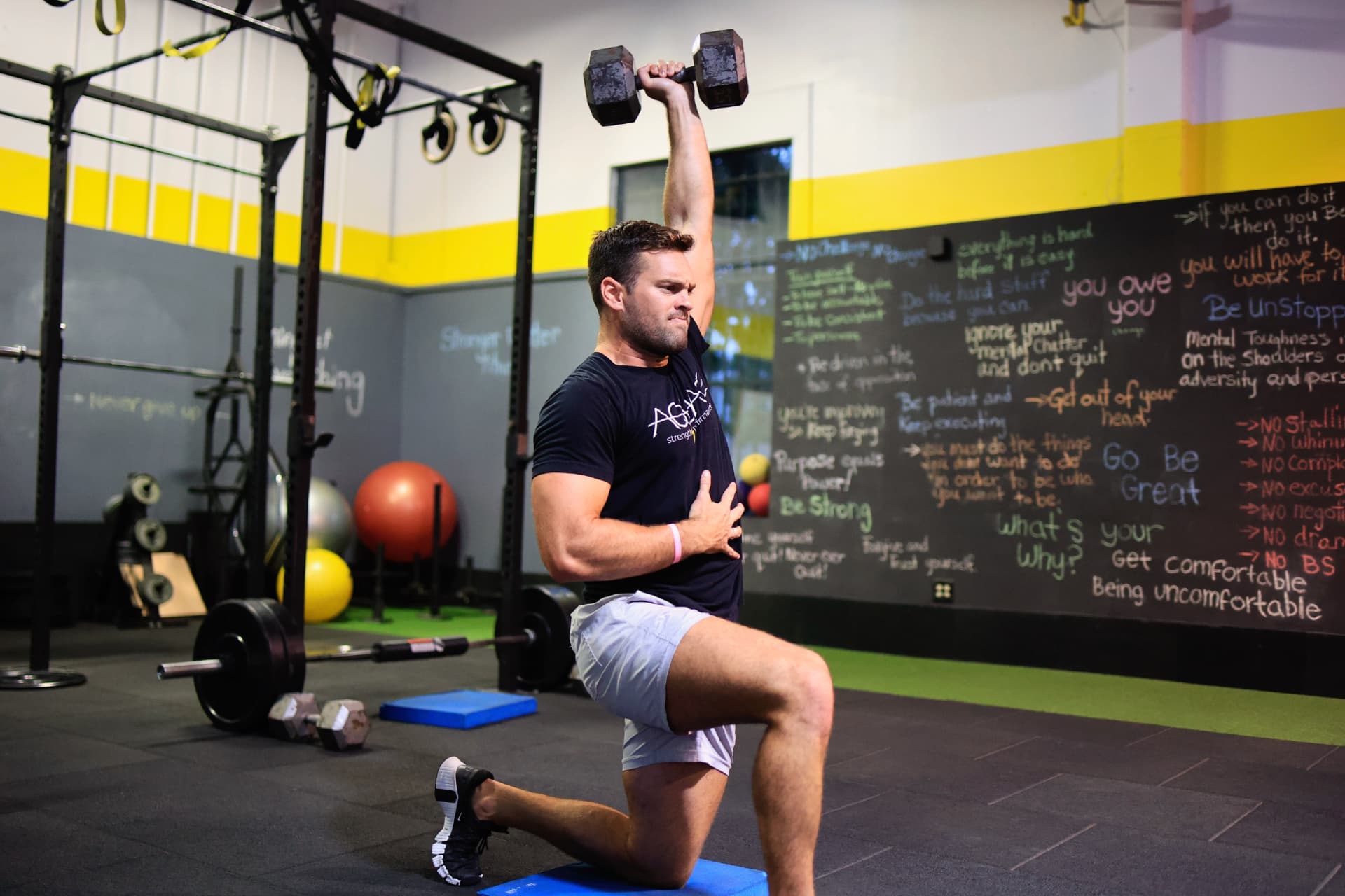 Coach Jack Brown pressing a dumbbell overhead from a half-kneeling position